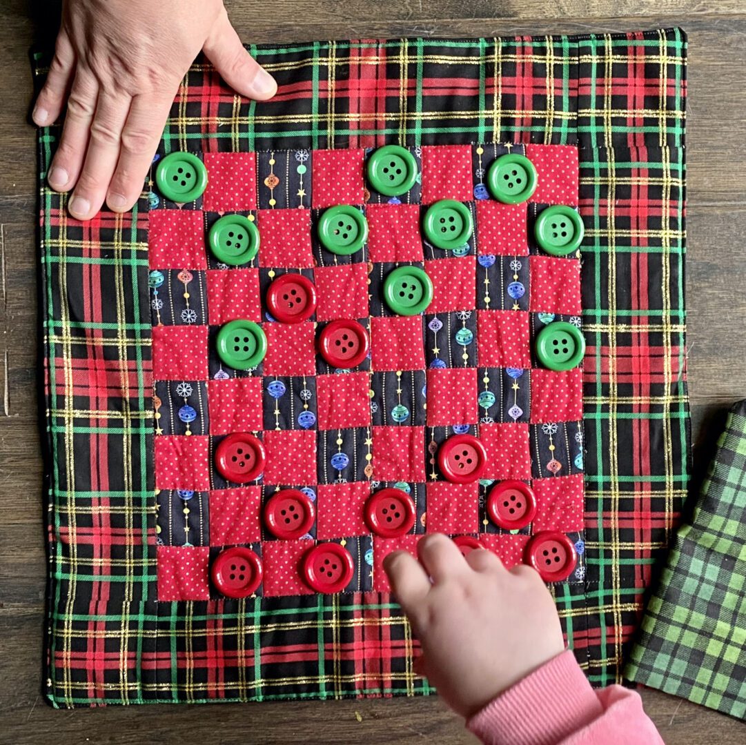 Two people playing Checkers on a wooden floor